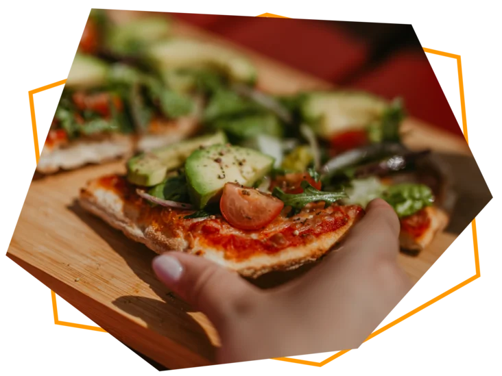 Servierte Pinsa Avocado Amore, welche zum Verzehr in die Hand genommen wird.
