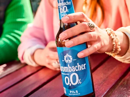 Eine Frau hält das alkoholfreie Krombacher o,0% in der Hand. 