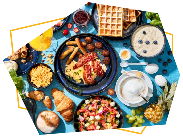 Draufsicht vom Frühstücksbuffet mit vielen leckeren Speisen auf blauen Untergrund.