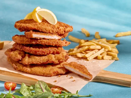 Gestapelte Schnitzel auf Brettchen mit blauem Hintergrund