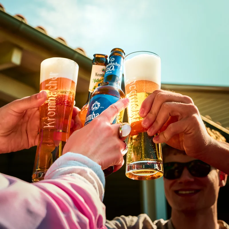 Freunde stoßen an mit frisch gezapften Krombacher, Krombacher Natur Radler und alkoholfreien Krombacher