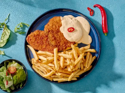 Draufsicht auf das Schnitzel Del Sol mit Beilagen drum herum.