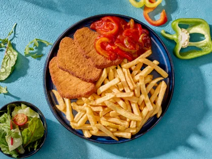 Draufsicht auf ein Schnitzel Puszta Art mit Beilagen drum herum.